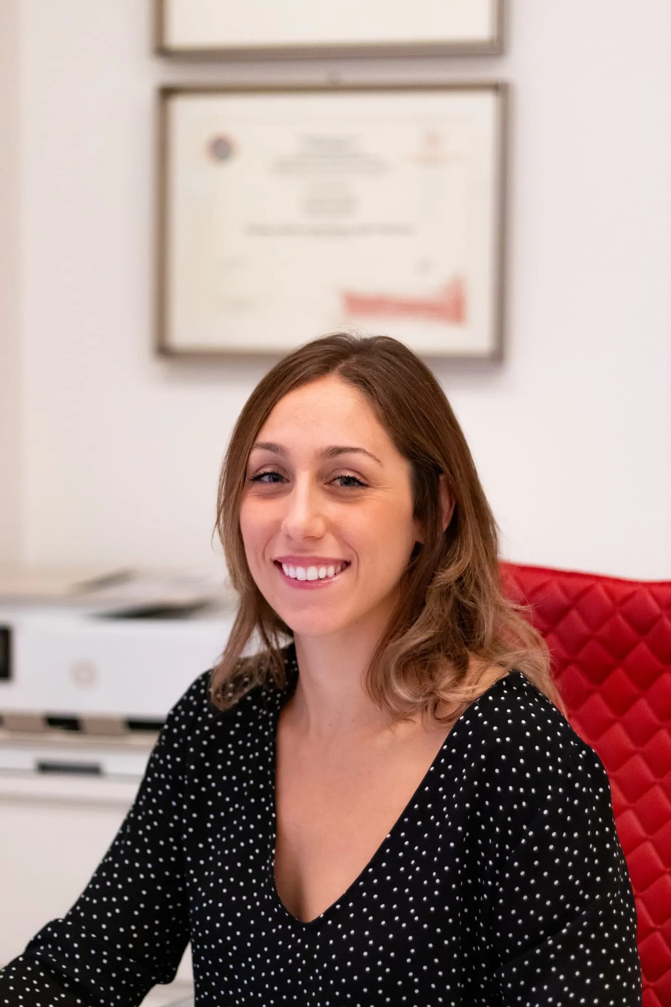 La dottoressa Carlotta Castelli sorridente nello studio, con il diploma alle spalle